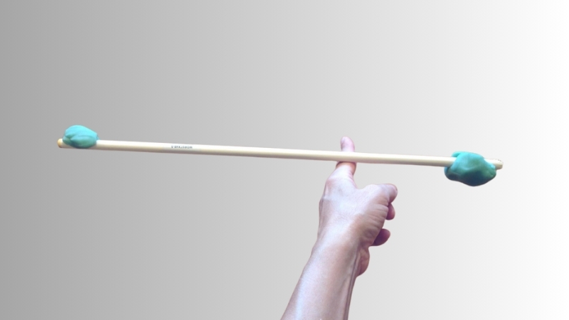 Ruka balansira drveni štap sa komadima gline na krajevima