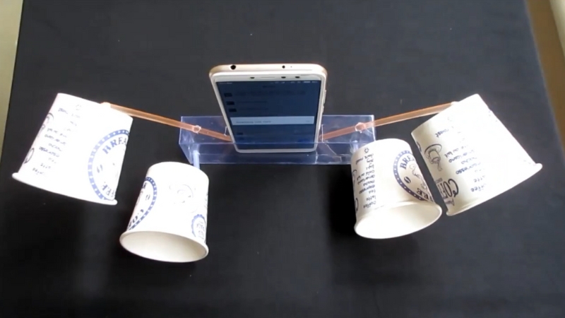 Telefon stoji na postolju, a sa strana su pričvršćene papirne čaše koje pojačavaju zvuk u jednostavnom školskom eksperimentu iz fizike