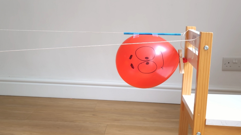 Crveni balon pričvršćen na kanap između dve stolice