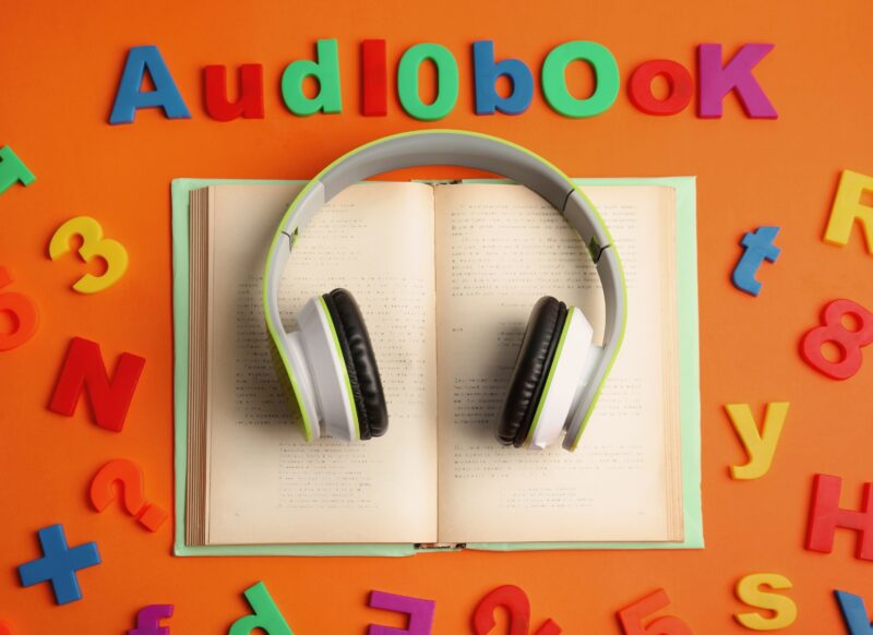 prikaz knjige i slušalica na narandžastoj pozadini sa slovima