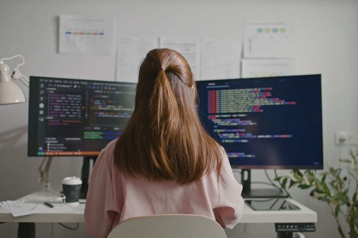 devojka sedi za kompjuterom i uči programiranje
